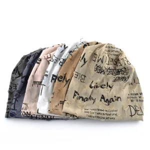 Vue détaillée de bonnets slouchy empilés avec tissu déchiré et imprimés de lettres stylisées.