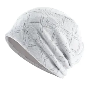 Vue détaillée d'un bonnet slouchy en tricot blanc avec une texture en résille losangée.