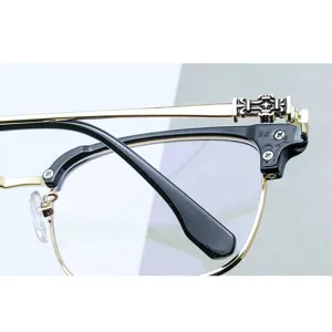 Primer plano de montura de gafas retro con motivo de cruz metálica y diseño de ceja elegante.