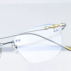 Monture de lunettes sans monture en titane pur avec verres taillés et croix dorée.