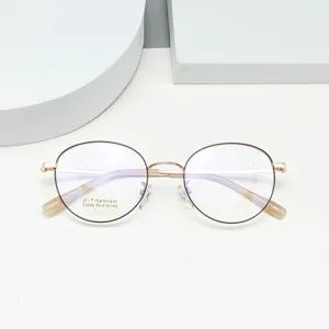 Detail view of round beta-titanium glasses frame with clear demo lens, gold thin rim.