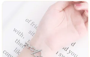 Close-up detailopname van een stijlvolle zilveren metalen kettingarmband met OT-sluiting op pols.