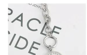 Detailopname van een zilveren metalen ketting met een vintage munt hanger, modern design.