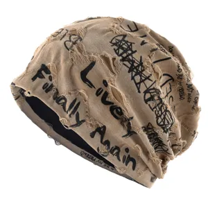 Vue détaillée du bonnet slouchy kaki usé avec des imprimés de graffiti noirs élégants.