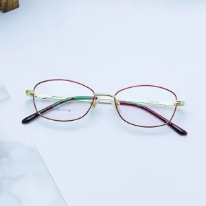 Women's metal full-frame optical glasses frame, elegant red and gold oval eyewear design.