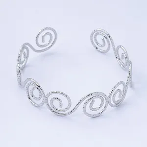 Bracciale aperto argentato con un design geometrico dettagliato a spirale d'onda.