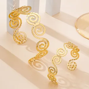Dettaglio set bracciale polsino cavo a spirale geometrica dorata, elegante gioiello di modo.