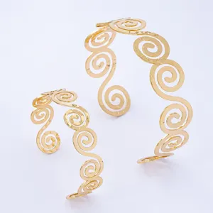 Dettaglio bracciale rigido con motivo a spirale dorato, design geometrico, gioiello elegante.