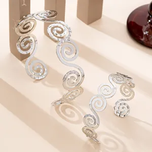 Vista di dettaglio del set bracciale polsino in metallo argento a spirale geometrica.