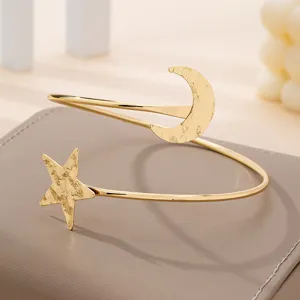 Prachtige gouden armcuff met ster en maanhangers en een getextureerde afwerking stijl.
