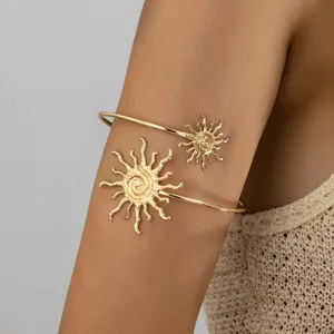 Gedetailleerde close-up van een gouden metalen zon motief open armmanchet armband, boho stijl.