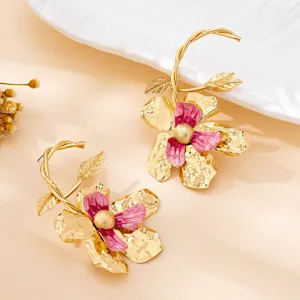 Detailopname van trendy vergulde bloemoorhangers met roze emaille bloemblaadjes en design.