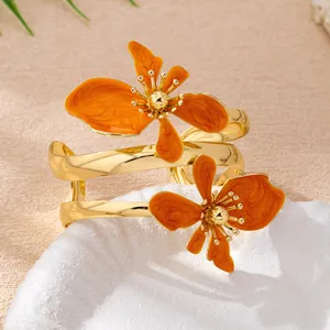 Goldener mehrlagiger Armreif mit leuchtenden orangefarbenen Emaille-Blumen, elegante Schmuck.