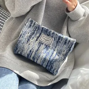 Blue textured clutch cosmetic bag with woven label, portable stylish storage pouch for daily use.