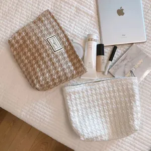 Detail view of stylish textured cosmetic bags in neutral tones, displayed in a neat setting.