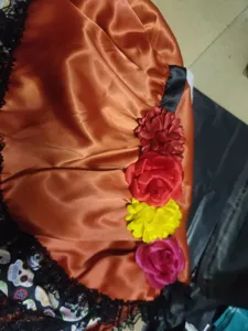 Detail view of Halloween skeleton skirt showcasing vibrant satin fabric, colorful flower accents.