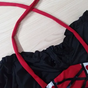 Gros plan détaillé du costume de reine rouge et noir, avec bretelles tour de cou et fronces.