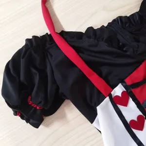 Gros plan détaillé du costume de reine noir et rouge avec manches bouffantes et cœurs.