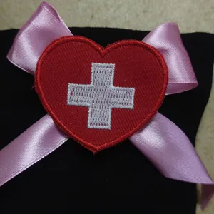 Primo piano dettaglio decorazione calzino infermiera con cuore rosso e croce ricamata.