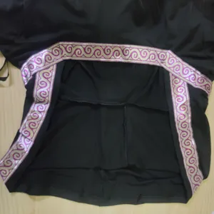 Vue détaillée d'un costume de sorcière médiévale noir avec bordure violette et argentée.