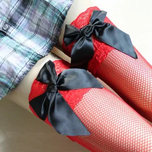 Detail view of red fishnet over-the-knee stockings featuring large black satin bows.