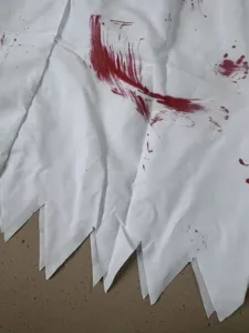 Detalle de tela disfraz enfermera zombi Halloween con dobladillo dentado blanco sangriento.