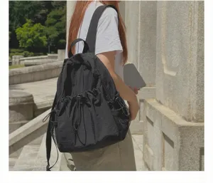 Detaillierte Nahaufnahme des stilvollen schwarzen Kordelzug-Rucksacks im Outdoor-Einsatz.