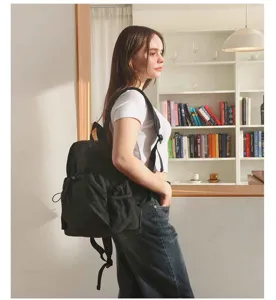 Detailansicht eines lässigen schwarzen Rucksacks, getragen von einem Model im Innenbereich.