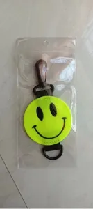 Fluorescerend gele smiley sleutelhanger met zwarte webbing en draaibare haak in detailweergave.