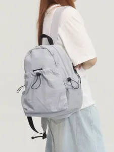 Grauer Damen Rucksack mit Kordelzug und Seitentaschen für den täglichen Weg zur Arbeit.