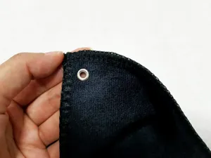 Detailansicht der schwarzen Golftuch-Ecke mit robuster Metallöse und feiner Overlock-Naht.