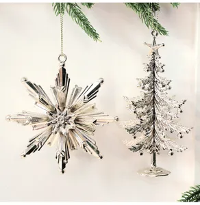 Nahaufnahme von silbernen Weihnachtsbaum- und Schneeflocken-Anhängern mit Pinienzweigen.