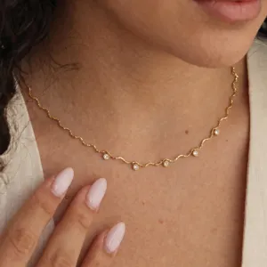 Collier ras de cou ondule dores delicat orne de pierres de zircone cubique brillantes.