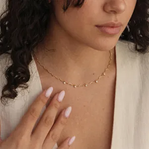 Gros plan détaillé d'un collier chaîne doré ondulé délicat avec des zircons brillants.