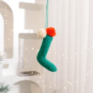Green knitted Christmas stocking hanging ornament with fluffy pom-poms for holiday tree decor