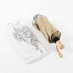 Detailed view of foldable sun umbrella with solid wood handle and elegant embroidered sleeve.