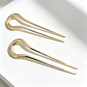 Closeup detail view of minimal gold U-shaped hair pins, elegant smooth metal finish for styling.