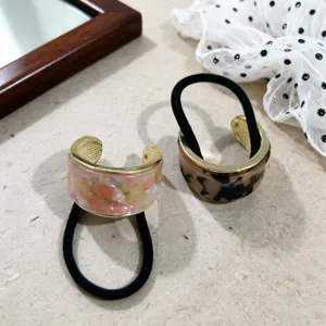 Chique halfronde haarelastiek met gouden metalen rand en trendy acetaat patroon detail.