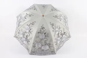 Élégant parapluie de soleil pliable avec broderie argentée, détail montrant une belle finition.
