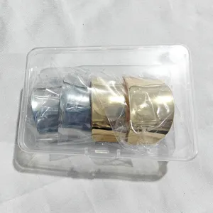 Vue de détail de manchettes de cheveux en métal doré et argenté dans une boîte plastique claire.