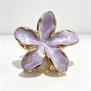 Primo piano dettagliato della pinza per capelli con fiore di plumeria viola e dorato.