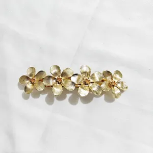 Primer plano detalle del elegante pasador de pelo de metal dorado con textura exquisita.