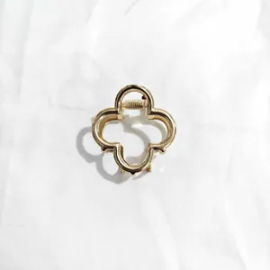 Gold clover hair claw detail shot, elegant metal shark clip for women's elegant updo styling.