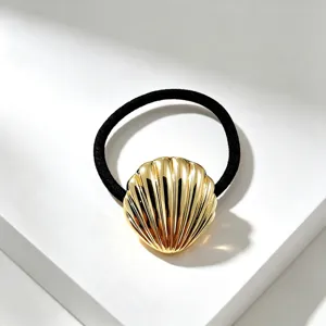 Gedetailleerde close-up van een chique gouden schelp haarelastiek met metalen accenten.