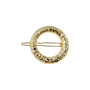 Dettaglio molletta per capelli rotonda in metallo dorato irregolare, elegante forcina.