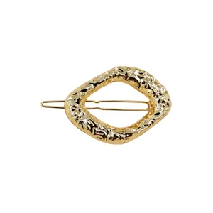 Dettaglio fermaglio per capelli in metallo geometrico irregolare oro, elegante molletta casual.