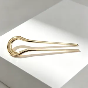 Detailed close-up of a minimalist gold alloy U-shaped hair fork with smooth finish.