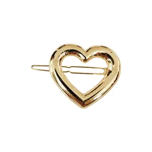 Primo piano sui dettagli della molletta per capelli a cuore in metallo dorato chic.