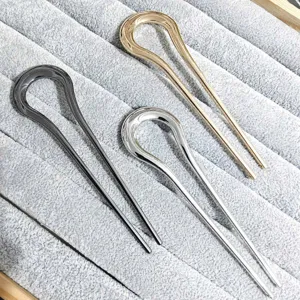 Close-up detail of sleek alloy U-shaped hair pins in gold, silver, and gunmetal.