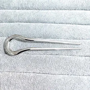 Detail view of a sleek silver U-shaped hair stick, minimalist metal hair fork for elegant buns.